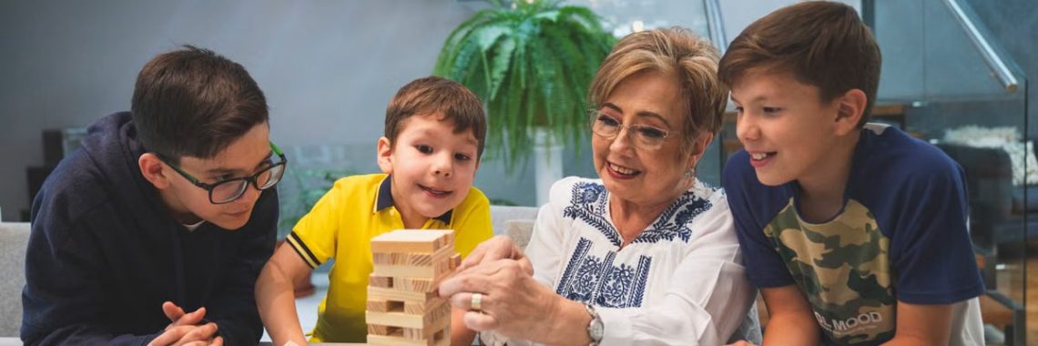A joyful family moment with grandma and grandsons playing Jenga indoors, capturing quality time together.
