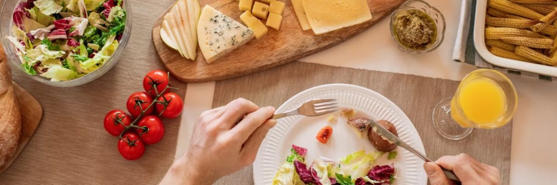 Overhead view of a cheese platter with fresh salad and juice, perfect for a gourmet lunch setting.